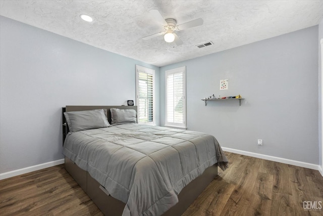 bedroom with wood finished floors, baseboards, a ceiling fan, and a textured ceiling