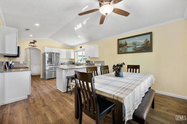 dining area featuring vaulted ceiling, wood finished floors, ceiling fan, baseboards, and crown molding