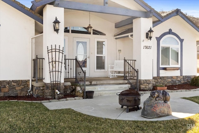view of exterior entry featuring stucco siding, stone siding, and covered porch