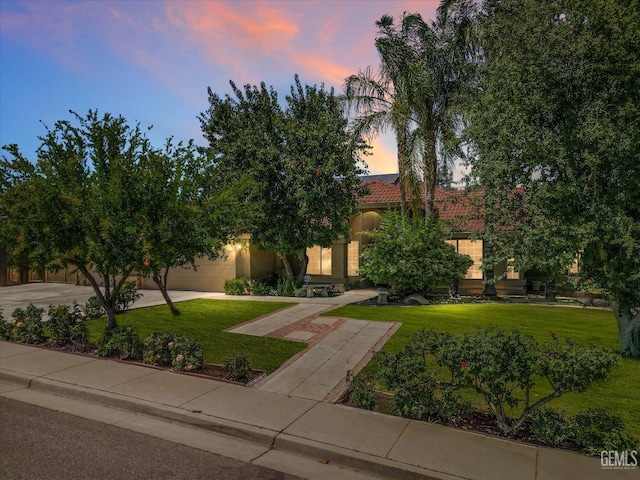 7310 Clifftop Way, Bakersfield, CA 93306 - view of property hidden behind natural elements with a front lawn, an attached garage, concrete driveway, a tile roof, and stucco siding