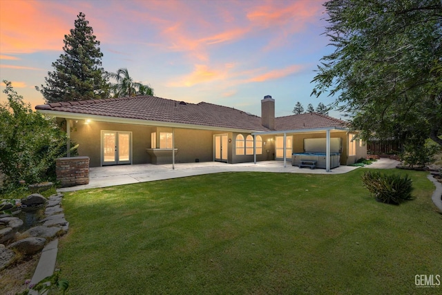 7310 Clifftop Way, Bakersfield, CA 93306 - back of house at dusk featuring a hot tub, french doors, a tile roof, and a patio area
