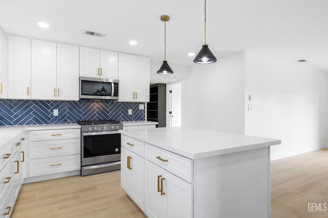 kitchen with decorative backsplash, light wood-style flooring, appliances with stainless steel finishes, a center island, and white cabinetry