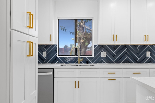 kitchen featuring light countertops, stainless steel dishwasher, a sink, and white cabinetry