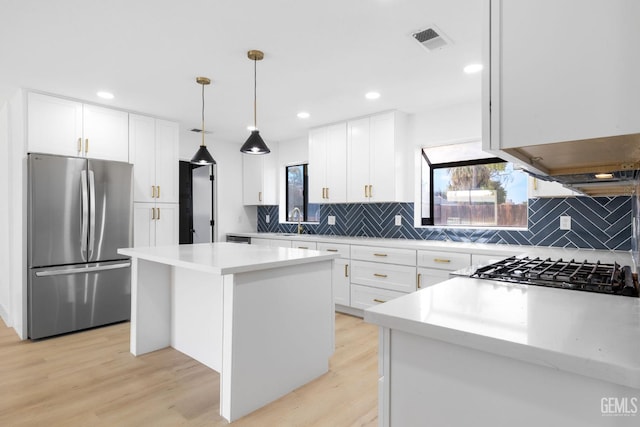 kitchen with a kitchen island, visible vents, a sink, light wood-type flooring, and freestanding refrigerator