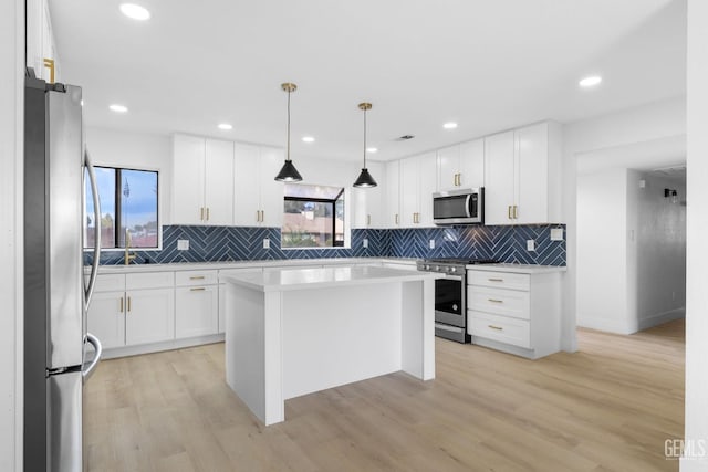 kitchen featuring stainless steel appliances, light wood finished floors, light countertops, and white cabinetry