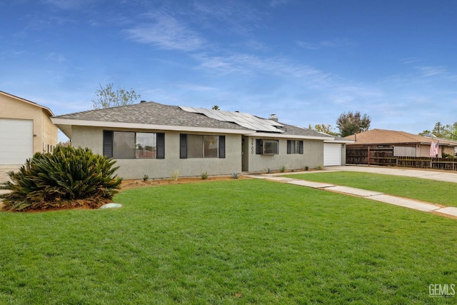 ranch-style house with fence, concrete driveway, roof mounted solar panels, stucco siding, and a front yard