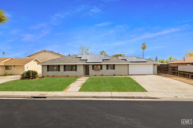 view of front facade featuring a garage, a front yard, and solar panels