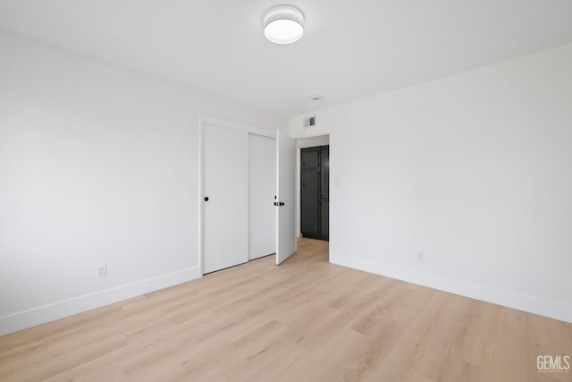 unfurnished room featuring light wood-style floors, visible vents, and baseboards