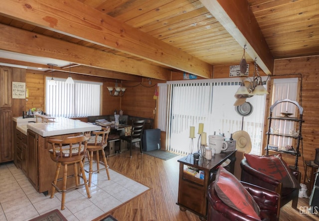 kitchen featuring decorative light fixtures, beam ceiling, kitchen peninsula, and a chandelier