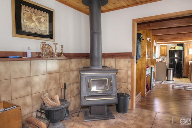 details with wooden ceiling, a wood stove, and black fridge