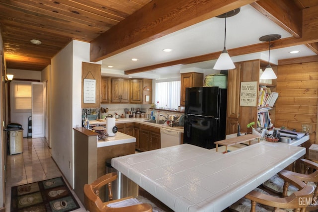 kitchen with dishwasher, tile countertops, black fridge, kitchen peninsula, and a kitchen breakfast bar