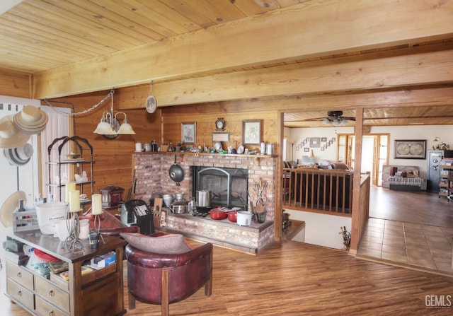 living room with ceiling fan, a brick fireplace, hardwood / wood-style floors, beamed ceiling, and wooden ceiling