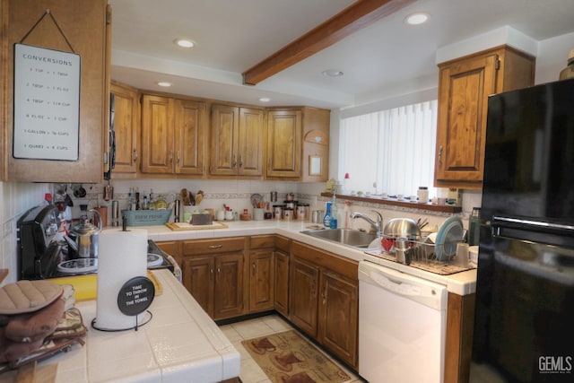 kitchen with beamed ceiling, sink, black fridge, tile countertops, and white dishwasher