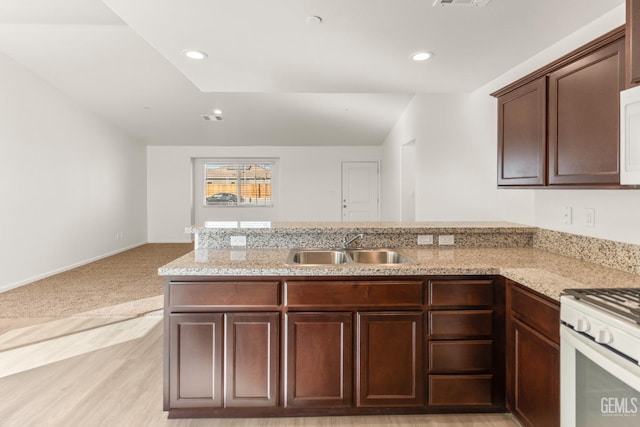 kitchen with dark brown cabinetry, sink, white appliances, and kitchen peninsula