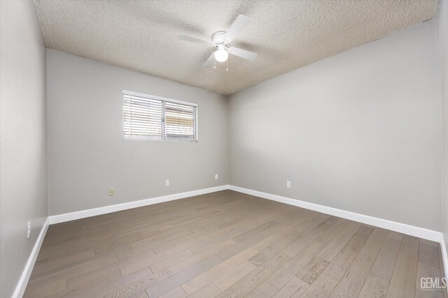 unfurnished room featuring a textured ceiling, wood finished floors, a ceiling fan, and baseboards