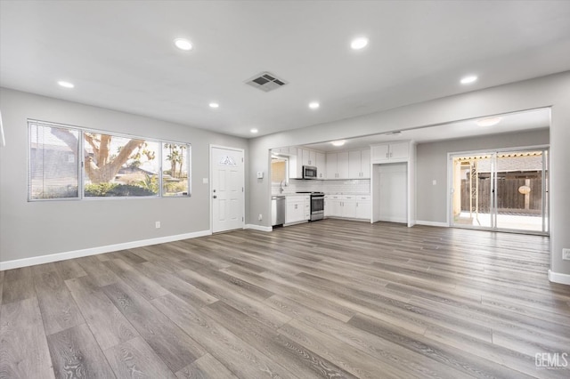 unfurnished living room with light wood-type flooring, visible vents, and recessed lighting