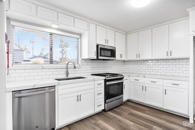 kitchen with appliances with stainless steel finishes, white cabinets, a sink, and dark wood-type flooring