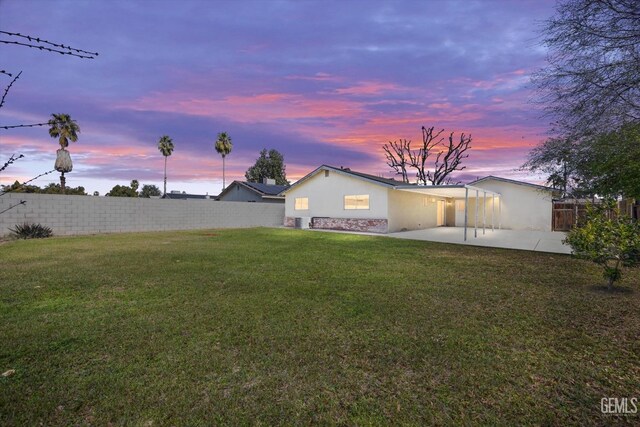 yard at dusk with a patio and a fenced backyard