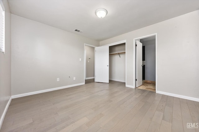 unfurnished bedroom with light wood-style floors, visible vents, baseboards, and a closet