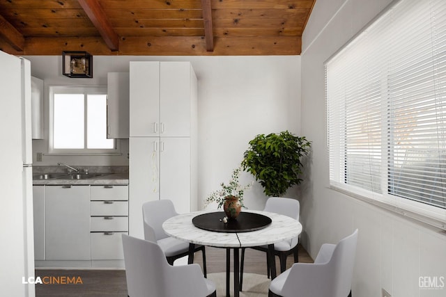 dining room featuring sink, hardwood / wood-style floors, vaulted ceiling with beams, and wood ceiling