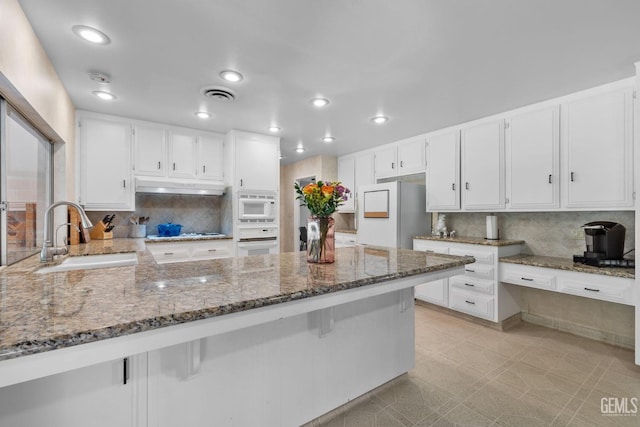 2513 Elm St, Bakersfield, CA 93301 - kitchen featuring a sink, white appliances, under cabinet range hood, stone counters, and decorative backsplash