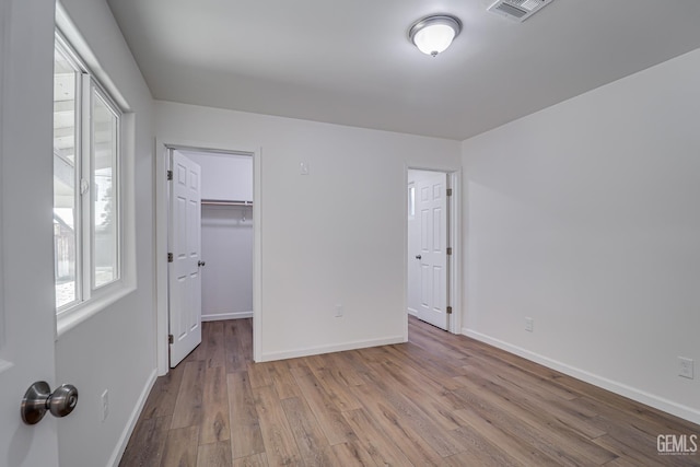 1201 Quincy St, Delano, CA 93215 - unfurnished bedroom with wood finished floors, multiple windows, baseboards, and a walk in closet