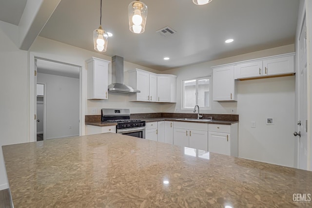 1201 Quincy St, Delano, CA 93215 - kitchen with stainless steel gas range, wall chimney exhaust hood, a sink, white cabinets, and decorative light fixtures