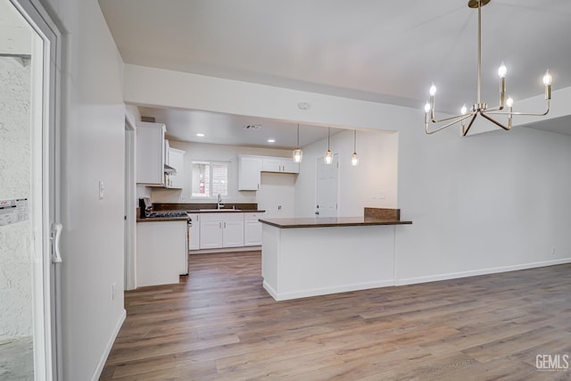 1201 Quincy St, Delano, CA 93215 - kitchen featuring dark countertops, stainless steel range with gas cooktop, a sink, wood finished floors, and a chandelier