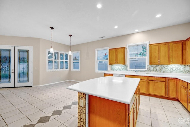 kitchen with decorative backsplash, light countertops, pendant lighting, brown cabinetry, and light tile patterned floors