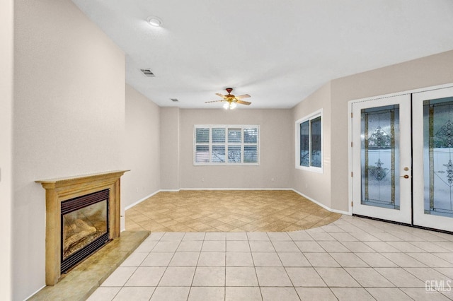 unfurnished living room with baseboards, visible vents, a glass covered fireplace, and a ceiling fan