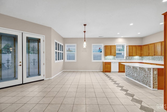 kitchen featuring light countertops, dishwasher, light tile patterned floors, baseboards, and decorative backsplash