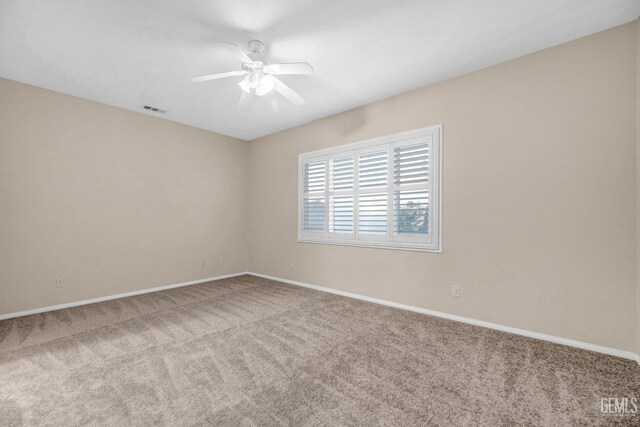empty room with baseboards, visible vents, ceiling fan, and carpet
