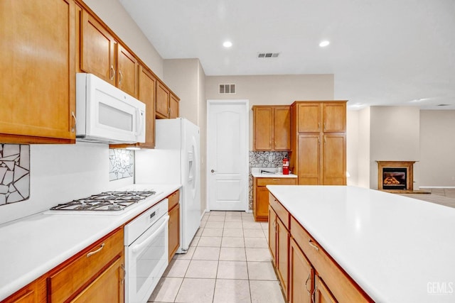 kitchen with light tile patterned flooring, light countertops, backsplash, white appliances, and visible vents