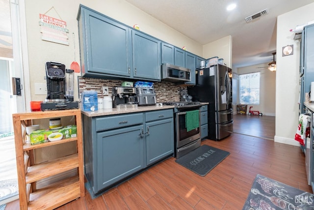 kitchen featuring ceiling fan, backsplash, dark hardwood / wood-style floors, appliances with stainless steel finishes, and blue cabinets