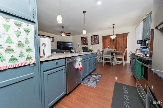 kitchen with decorative light fixtures, ceiling fan, sink, appliances with stainless steel finishes, and blue cabinetry