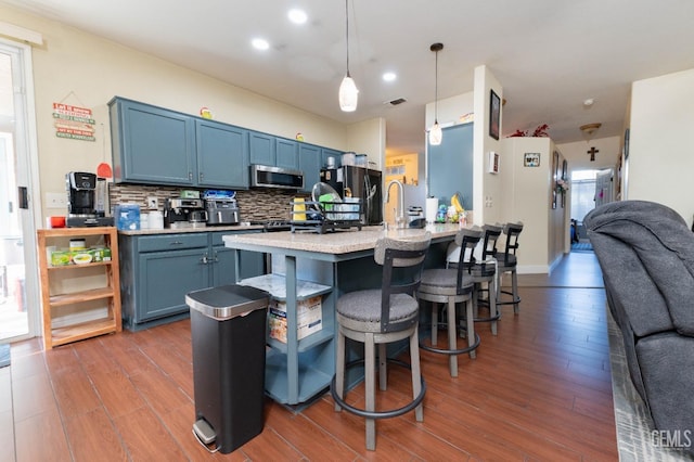 kitchen with decorative light fixtures, backsplash, a kitchen breakfast bar, and blue cabinetry