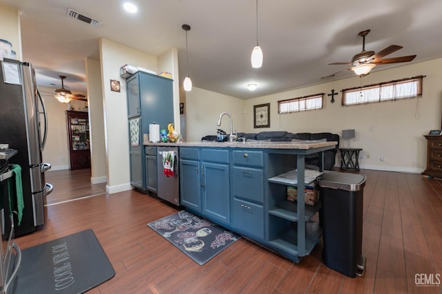 kitchen featuring pendant lighting, kitchen peninsula, sink, blue cabinetry, and stainless steel fridge