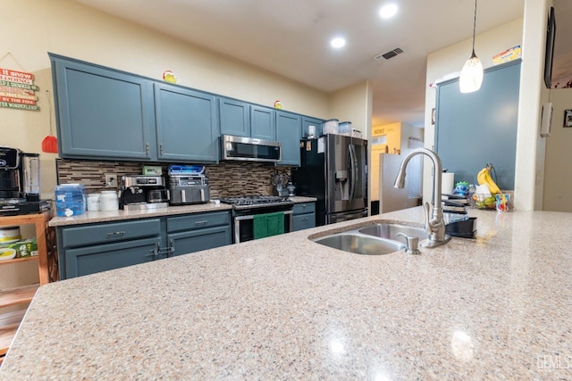 kitchen with pendant lighting, decorative backsplash, sink, stainless steel appliances, and blue cabinets