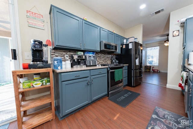 kitchen featuring ceiling fan, appliances with stainless steel finishes, tasteful backsplash, dark hardwood / wood-style flooring, and blue cabinets