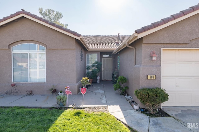 doorway to property featuring a garage, a patio area, and a yard