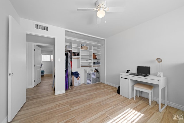 home office with ceiling fan, light wood-style flooring, visible vents, and baseboards