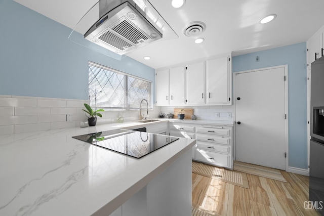 kitchen with black electric stovetop, visible vents, backsplash, white cabinets, and a sink