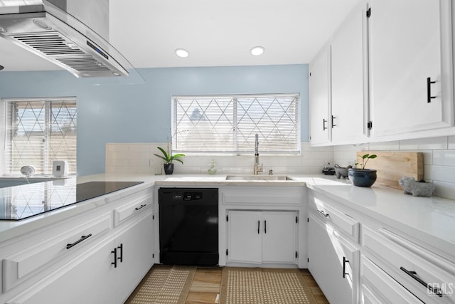 kitchen with white cabinets, decorative backsplash, range hood, black appliances, and a sink