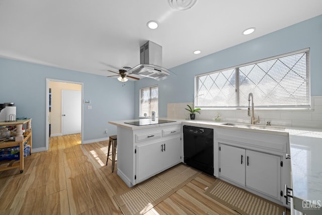 kitchen with a peninsula, black appliances, light countertops, and a sink