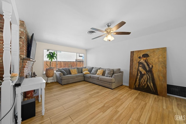 living room with light wood-style floors, visible vents, a ceiling fan, and ornate columns