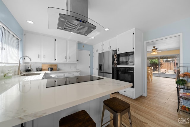 kitchen featuring plenty of natural light, black appliances, a peninsula, and decorative backsplash