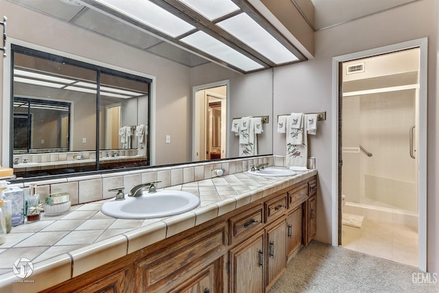bathroom with double vanity, a sink, and a stall shower