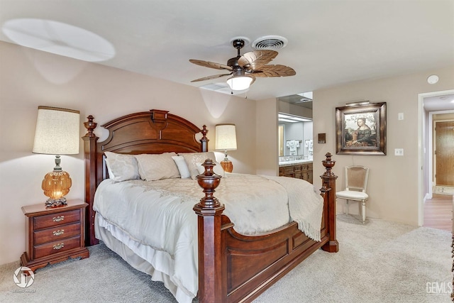 bedroom with visible vents, a ceiling fan, ensuite bath, and light carpet
