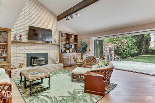 living room featuring a healthy amount of sunlight, beamed ceiling, rail lighting, and wood finished floors