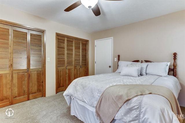 carpeted bedroom with two closets and a ceiling fan
